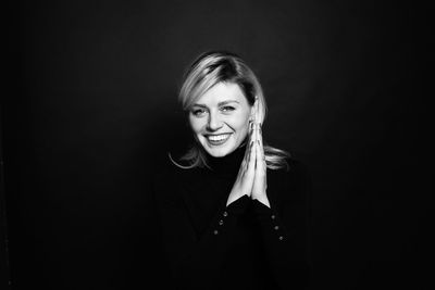Portrait of smiling young woman against black background