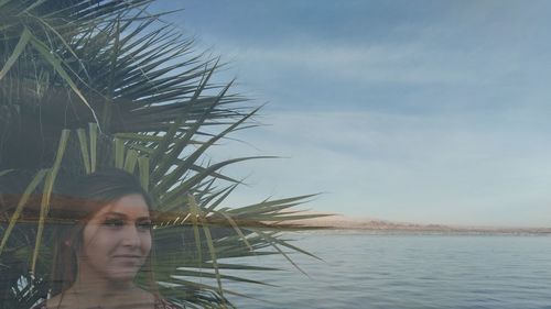 Portrait of young woman looking away against sky