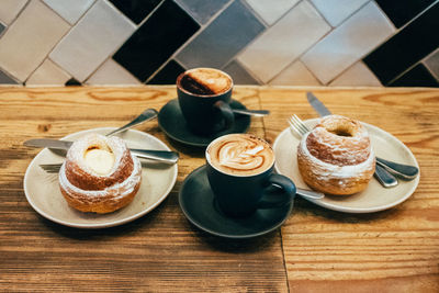 Two coffees and two desserts on a wooden table in a cafe setting, desserts and cappuccino to enioy