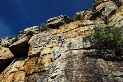 Low angle view of person on rock against sky