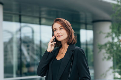 Young businesswoman standing against buildings