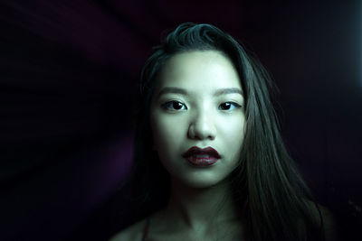 Portrait of beautiful young woman against black background