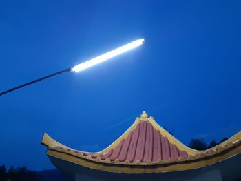 Low angle view of illuminated lamp against clear blue sky