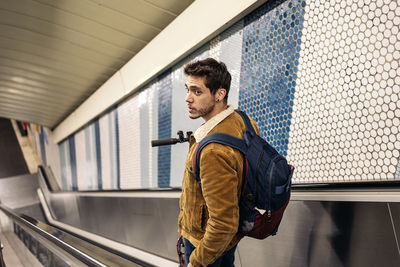 Man in stylish outfit with electric scooter in the mechanic stair of underground