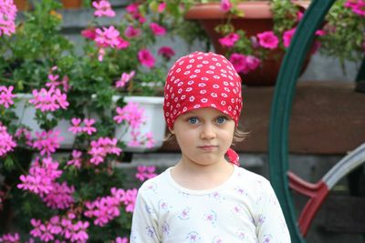 Portrait of girl wearing bandana standing against potted plants in yard