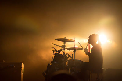 Silhouette man standing on stage against sky during sunset