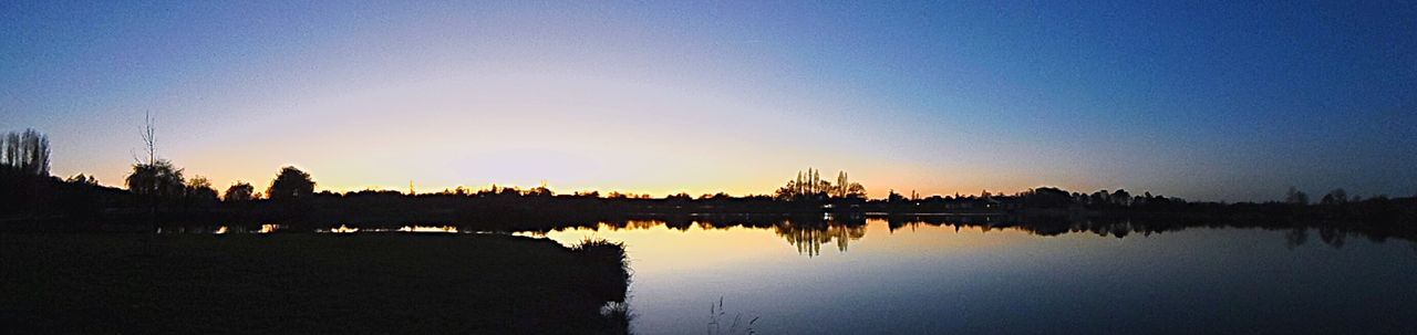 water, clear sky, copy space, silhouette, reflection, sunset, tranquil scene, tranquility, scenics, waterfront, beauty in nature, blue, lake, nature, dusk, standing water, sea, built structure, idyllic, calm