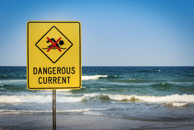 Information sign on beach against clear sky