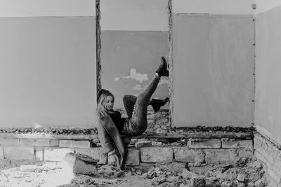 Full length of woman sitting in abandoned building