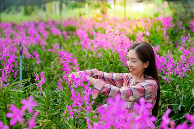 Portrait of young woman standing amidst plants