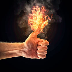 Fire igniting on man thumb against black background