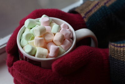 Cropped hand holding hot chocolate by window