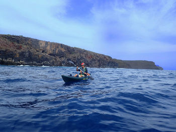 Man kayaking in river against sky