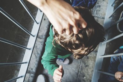 Cropped hand of woman holding boy hair on footbridge