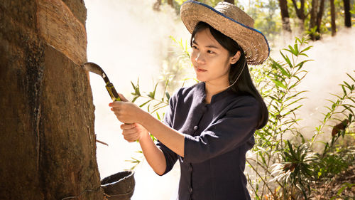 Woman collecting a latex from a rubber tree