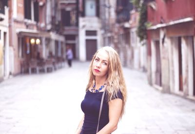 Portrait of beautiful young woman standing in city