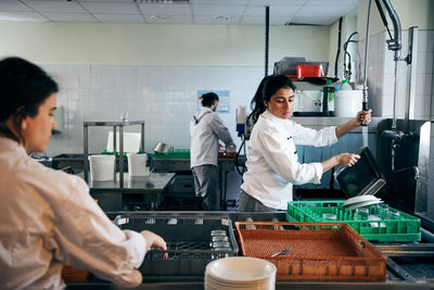 Female chef washing dishes in commercial kitchen