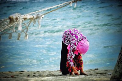 Rear view of woman with umbrella against sea