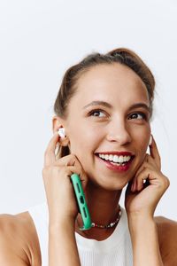 Portrait of smiling young woman using mobile phone against white background
