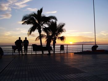 Silhouette people at swimming pool against sky during sunset