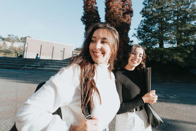 Smiling female friends walking at college campus