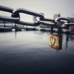 Close-up of padlock on chain over bay