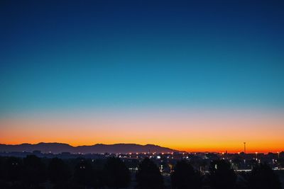 Illuminated cityscape against clear sky at sunset