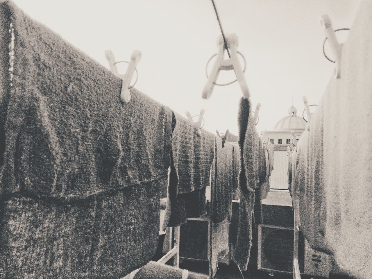 LOW ANGLE VIEW OF CLOTHES DRYING ON CLOTHESLINE AGAINST BUILDINGS