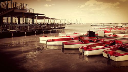 Boats moored at harbor against sky