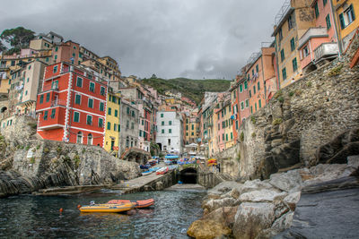 Inflatable boats moored in sea by manarola against cloudy sky