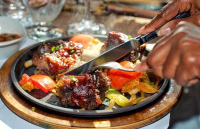 High angle view of diverse woman cutting steak on a plate with vegetables at dinner in restaurant 