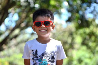 Portrait of smiling boy in sunglasses standing outdoors