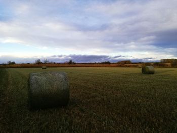 Hay bales on field against sky