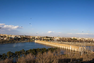 Scenic view of river by city against blue sky