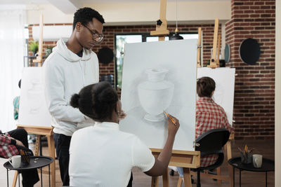 Rear view of woman sketching at workshop