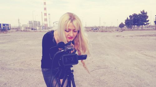 Woman photographing on road against sky