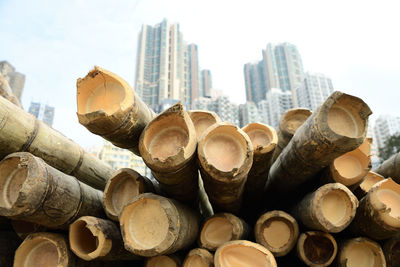 Close-up of stack of logs in city against sky