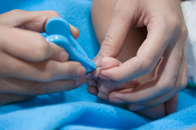 Close-up of mother cutting nails of baby at home