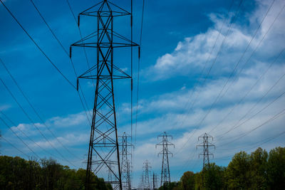 Low angle view of electricity pylon against blue sky