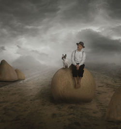 Surreal portrait of an older dog with its owner sitting on a rock in the middle of a path.