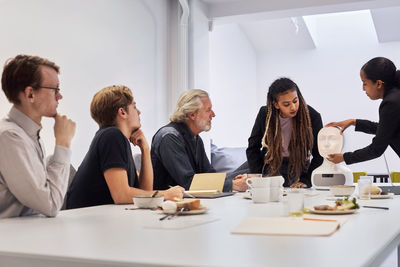 Business people discussing robot voice assistant during meeting