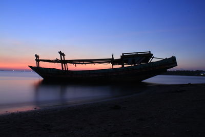 Silhouette boat on beach against sky during sunset