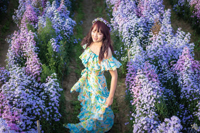 Portrait of smiling woman standing amidst purple flowers