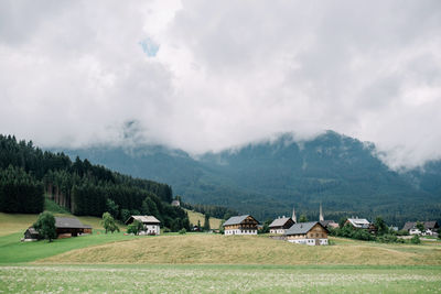 Houses on field by buildings against sky