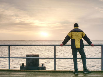 Man tourist in autumn mist on wooden pier above sea. depression dark atmosphere.