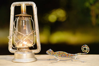Lizard shape figurine by oil lamp on table