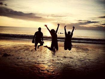 Friends jumping on beach at sunset