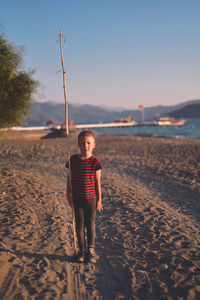 Boy standing at beach against sky
