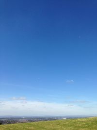 Scenic view of grassy field against blue sky