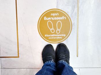 Low section of man standing by text on floor